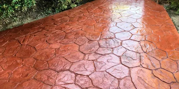 Pavimento de hormigón impreso en color terracota con dibujo de piedra irregular