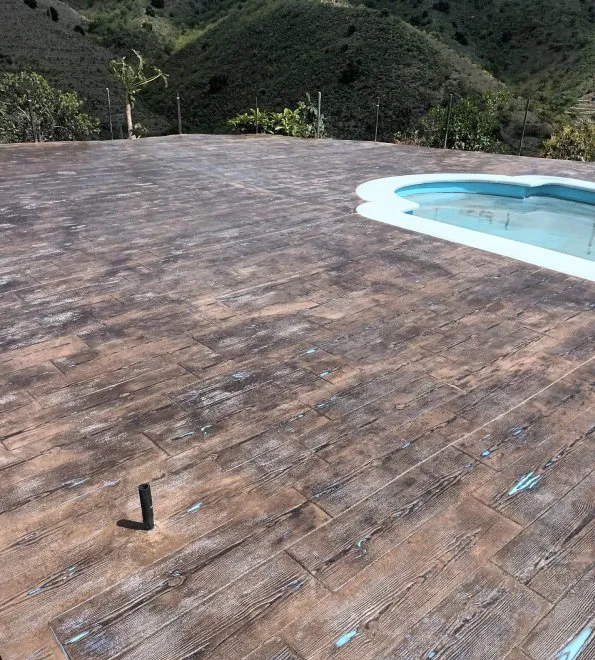 Detalle del suelo de hormigón impreso imitación madera junto a la piscina
