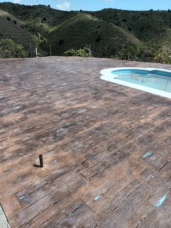 Suelo de hormigón impreso imitación madera junto a una piscina