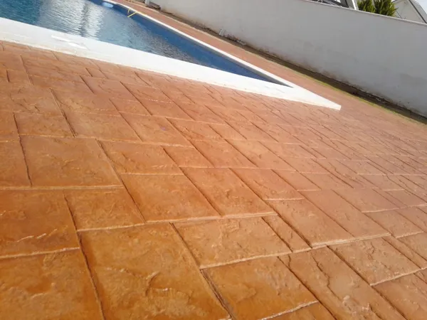 Hormigón impreso terracota con dibujo de losa junto a una piscina