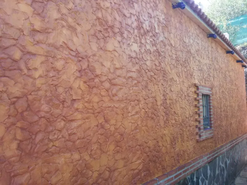 Fachada de vivienda revestida con hormigón impreso vertical en tono ocre