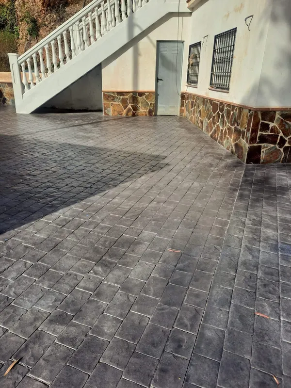 Patio frente a una vivienda con hormigón impreso gris