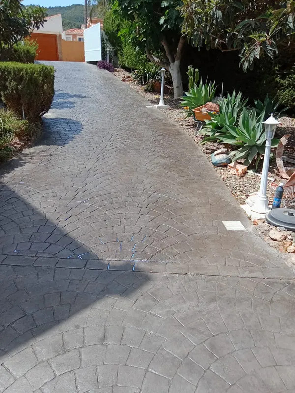 Camino de acceso entre jardines con hormigón impreso gris